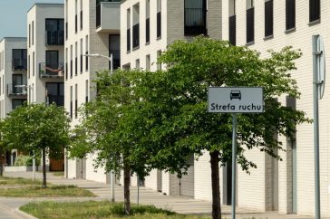 Contemporary apartment buildings with green trees on a sunny street in Wrocław, Poland.